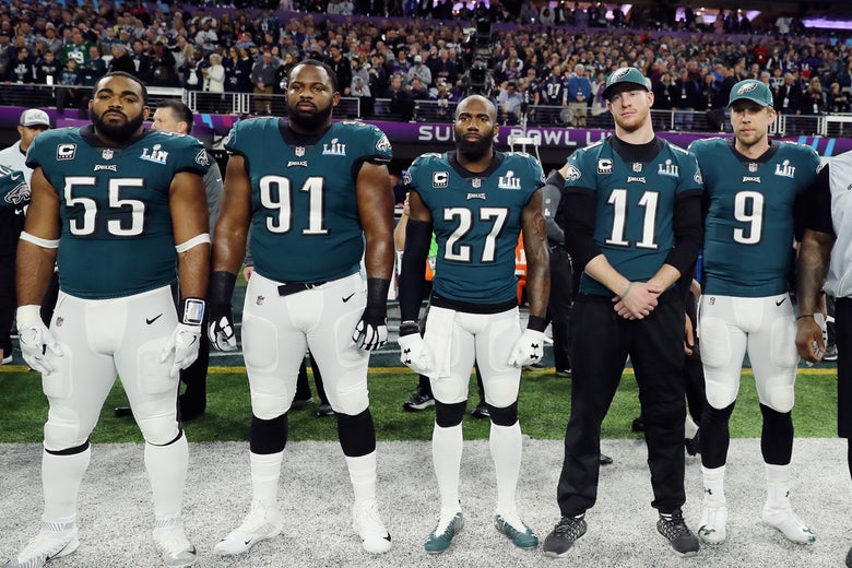 Five Eagles players stand on the sideline facing toward the camera.